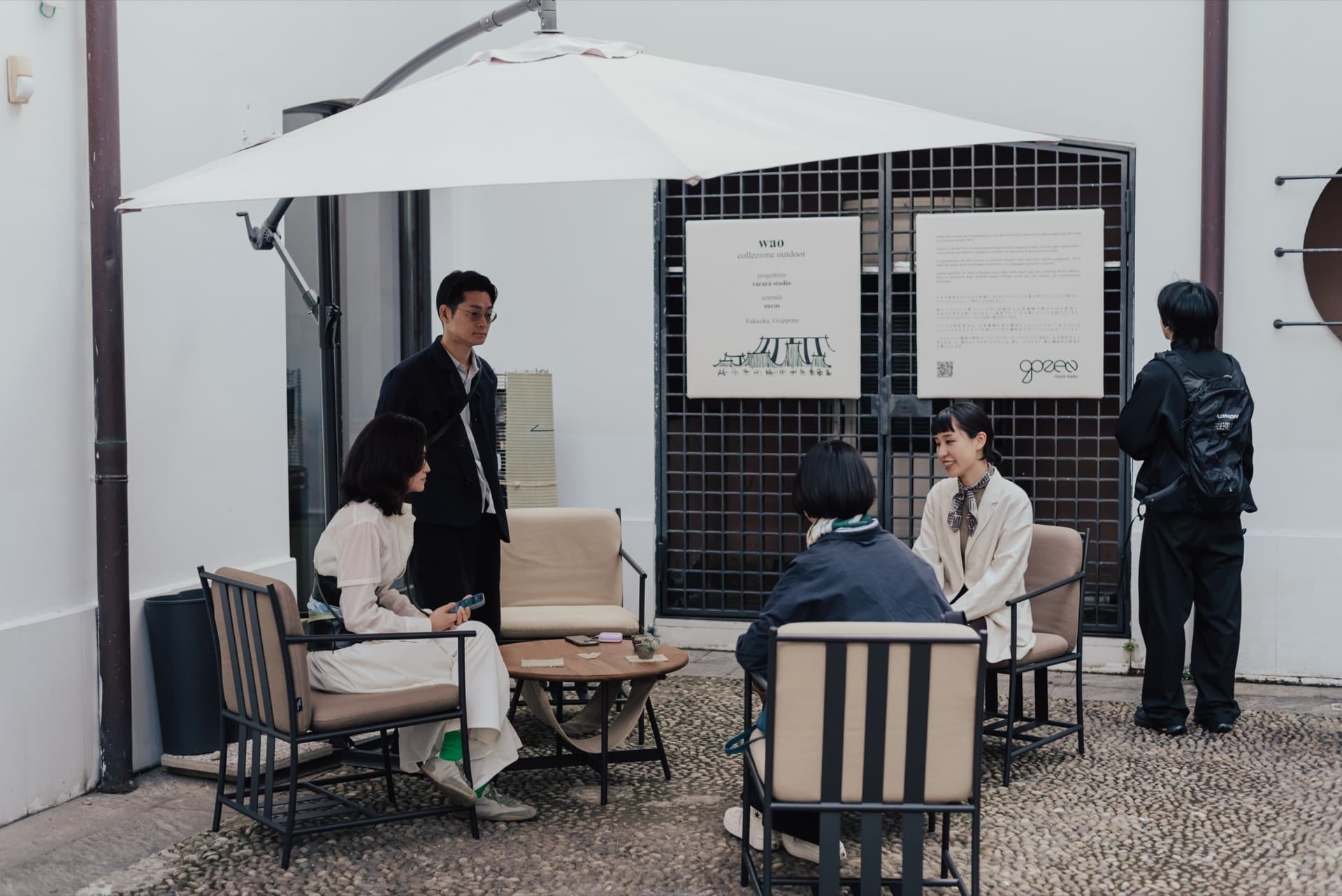 Persone sedute in cortile accanto all'esposizione della collezione outdoor WAO