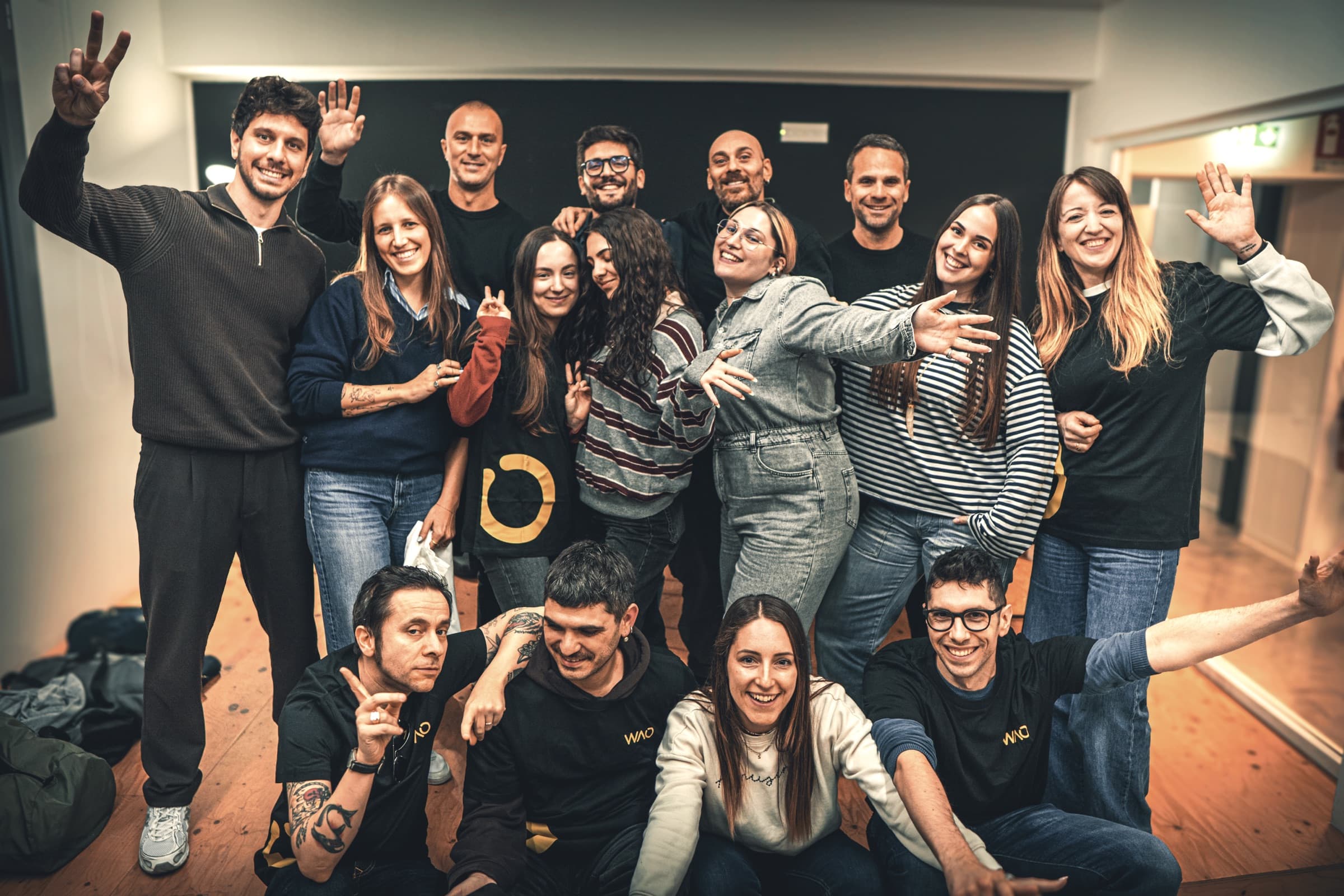 The WAO team together, waving and smiling, in one of our Milan spaces